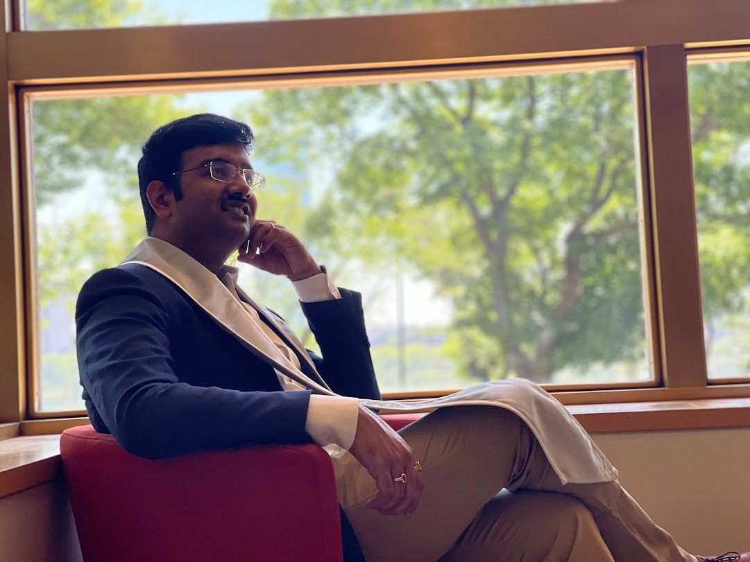Somesh Mohapatra seated by a window in a suit, in a thoughtful pose